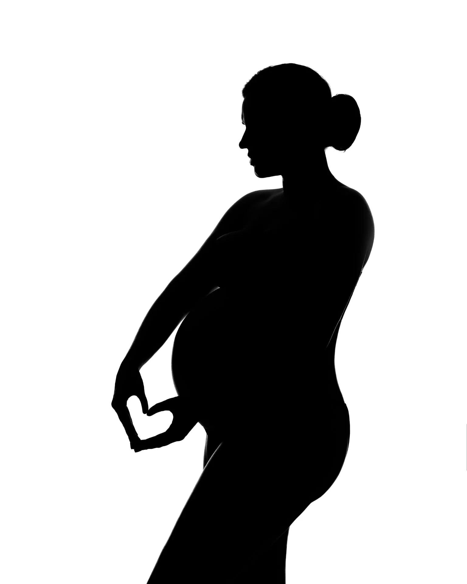 Silhueta de gestante em preto e branco formando coração com as mãos