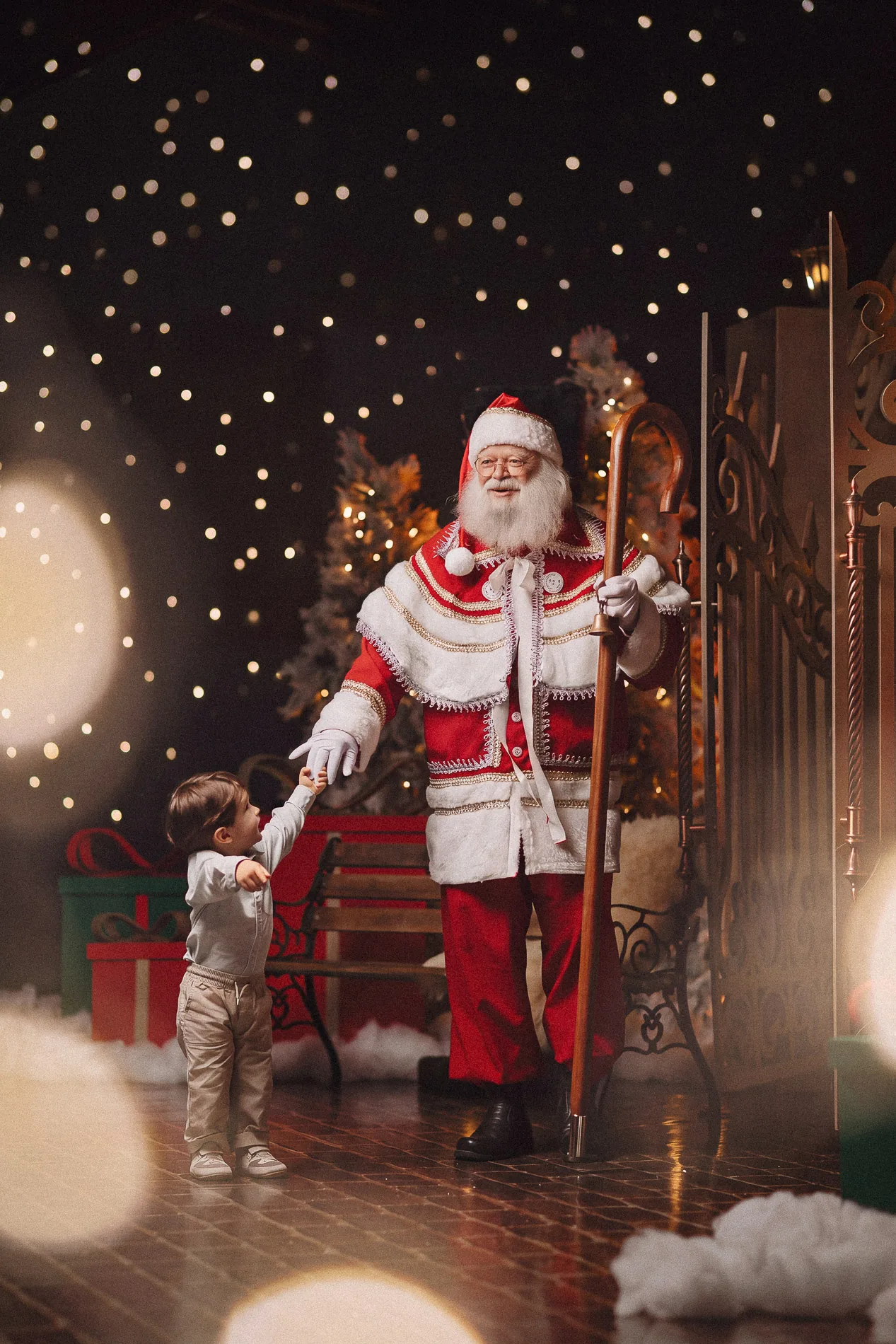 Papai Noel com seu cajado entre as árvores e as luzes de Natal.