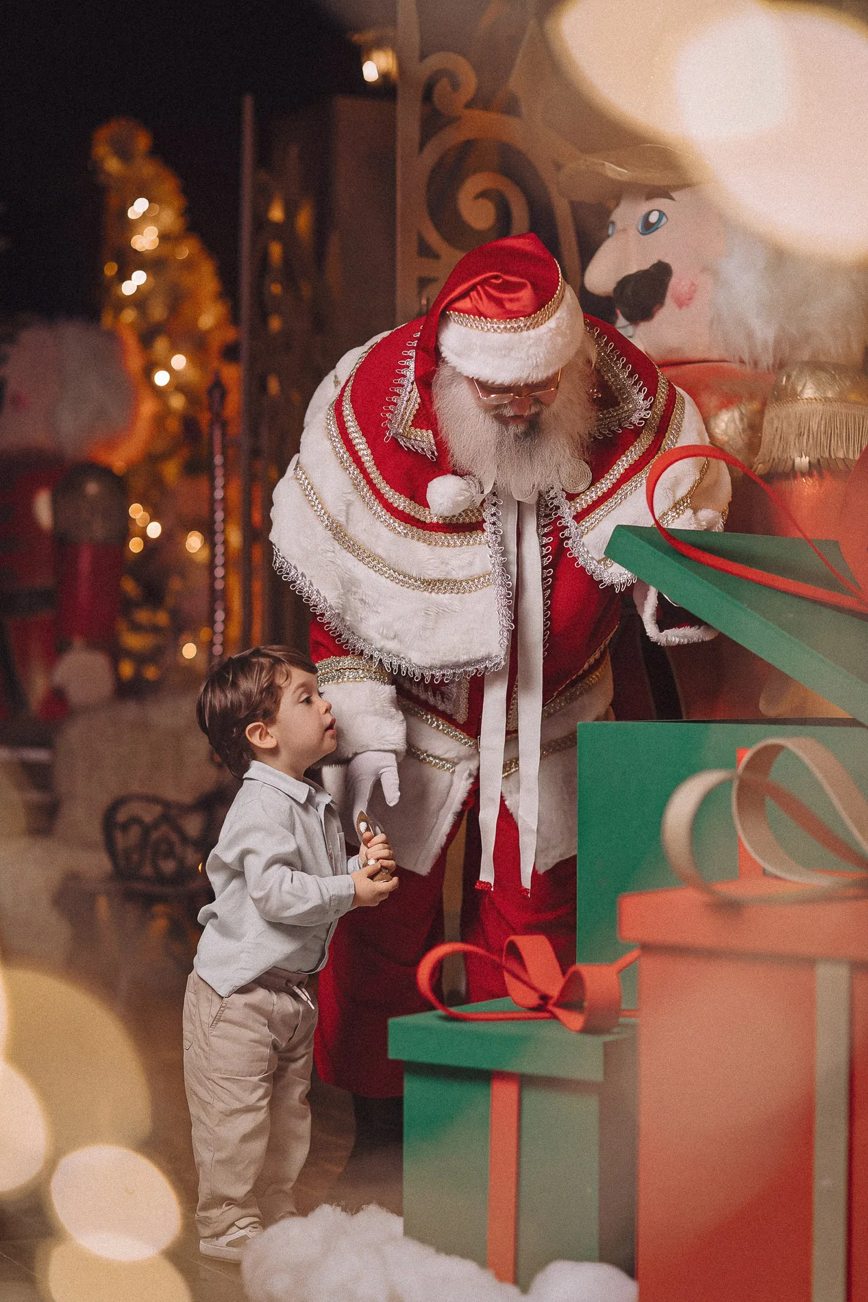 Criança explorando uma caixa de presente com Papai Noel.